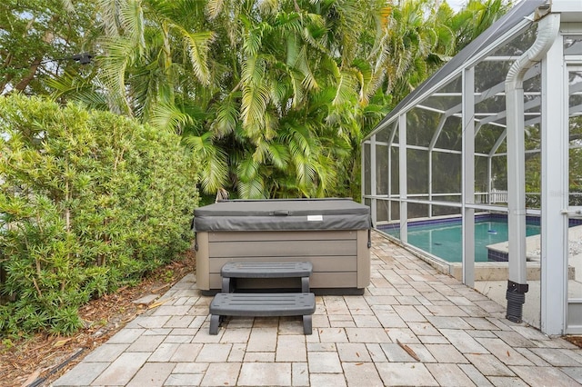 view of patio with glass enclosure and a pool with hot tub