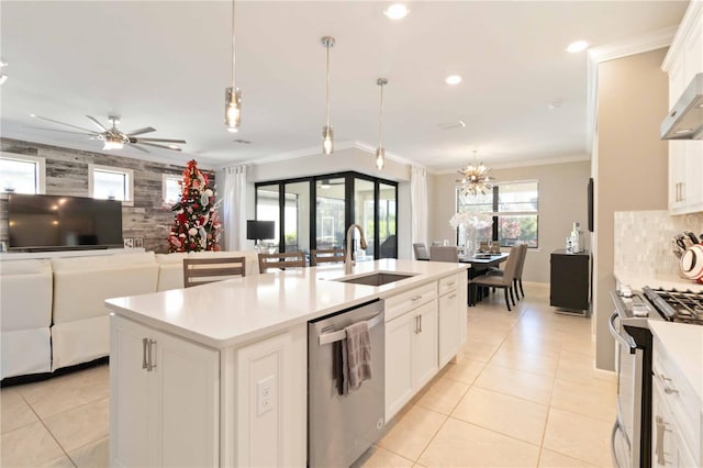 kitchen with stainless steel appliances, sink, white cabinetry, hanging light fixtures, and an island with sink