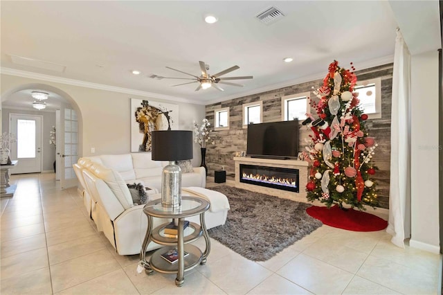 tiled living room with a wealth of natural light, crown molding, and ceiling fan