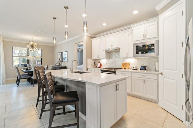 kitchen with pendant lighting, a center island with sink, sink, built in microwave, and white cabinetry