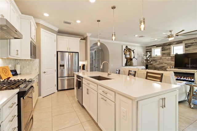 kitchen with white cabinets, appliances with stainless steel finishes, a center island with sink, and sink