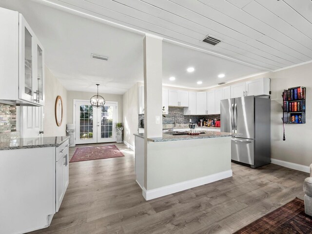 kitchen featuring light stone countertops, french doors, white cabinets, hardwood / wood-style floors, and stainless steel refrigerator