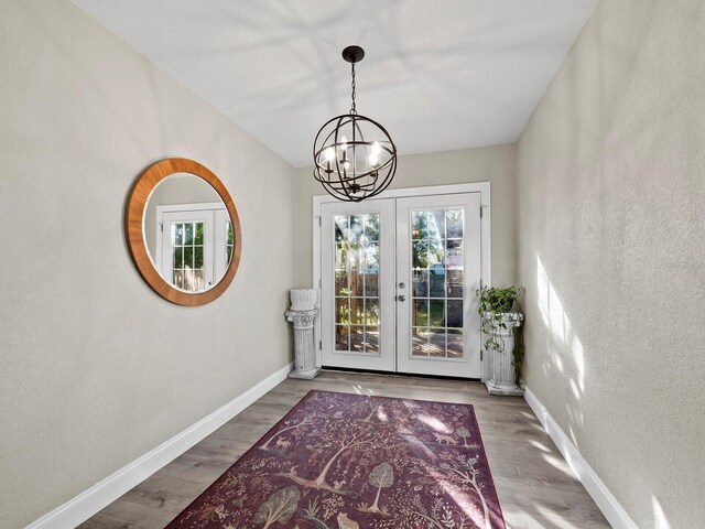 doorway with french doors, an inviting chandelier, and hardwood / wood-style floors