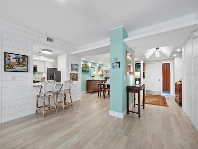 kitchen with kitchen peninsula, appliances with stainless steel finishes, a breakfast bar, light hardwood / wood-style flooring, and white cabinets