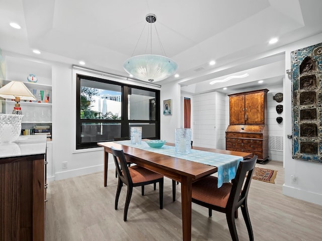 dining area featuring light hardwood / wood-style flooring and a tray ceiling