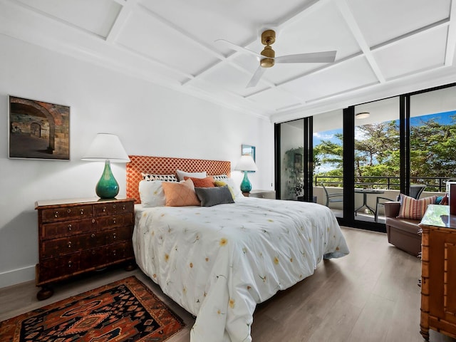 bedroom with expansive windows, light hardwood / wood-style floors, ceiling fan, and coffered ceiling