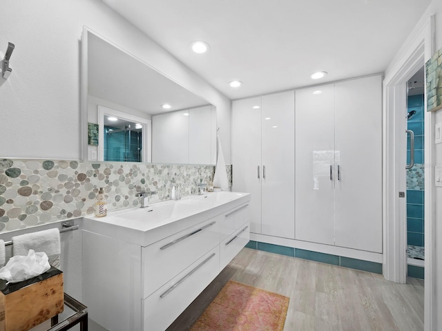 bathroom featuring hardwood / wood-style floors, vanity, an enclosed shower, and backsplash