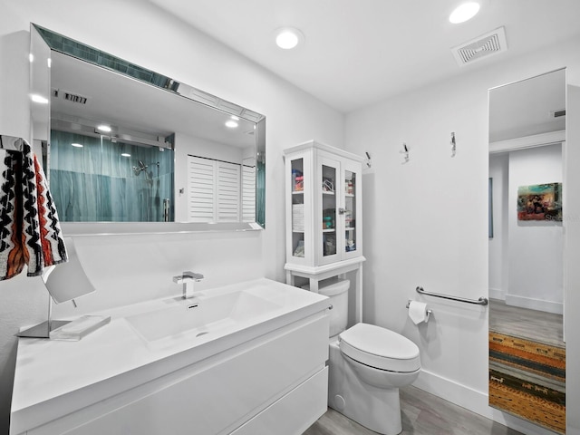 bathroom with hardwood / wood-style floors, vanity, a shower with door, and toilet