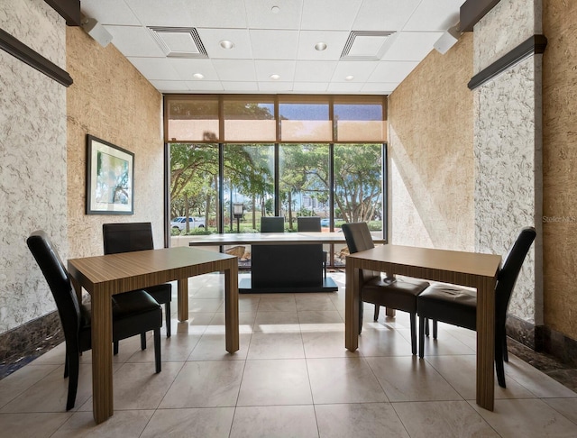 dining area with a high ceiling, a wall of windows, and light tile patterned flooring