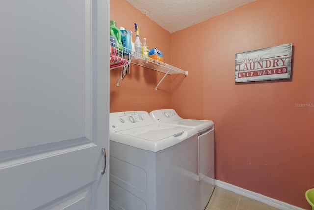 washroom with light tile patterned flooring, a textured ceiling, and washing machine and clothes dryer