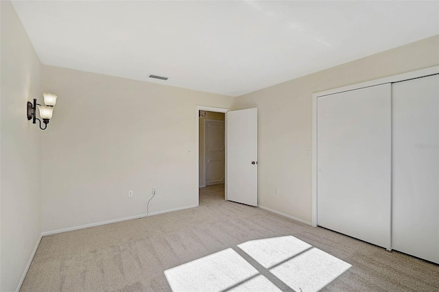 unfurnished bedroom featuring light carpet and a closet