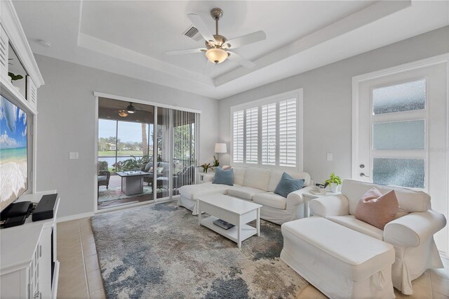 living room with ceiling fan, light tile patterned floors, and a raised ceiling