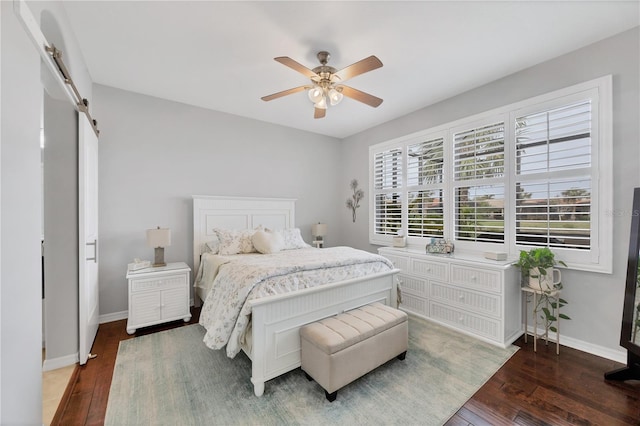 bedroom featuring ceiling fan, a barn door, and dark wood-type flooring