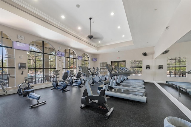 gym featuring a raised ceiling and ceiling fan