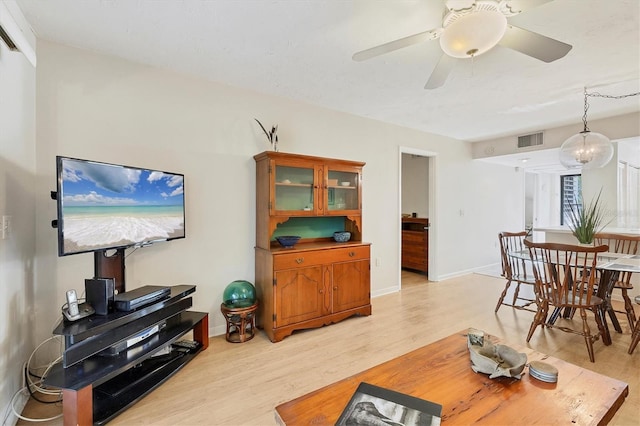 living room featuring ceiling fan with notable chandelier and light wood-type flooring