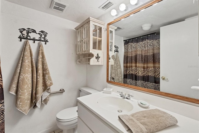 bathroom with vanity, a textured ceiling, toilet, and walk in shower