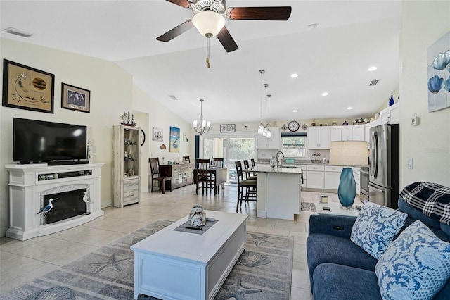 living room featuring sink, a high end fireplace, vaulted ceiling, light tile patterned flooring, and ceiling fan with notable chandelier