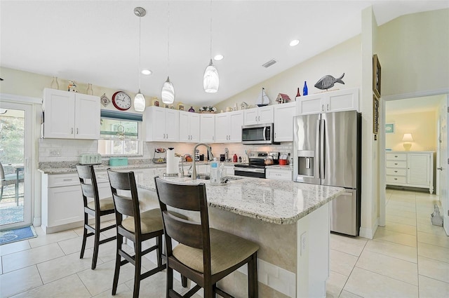 kitchen featuring a center island with sink, white cabinets, pendant lighting, and appliances with stainless steel finishes