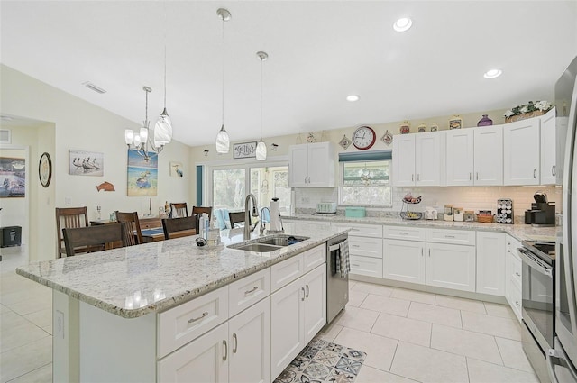 kitchen with pendant lighting, a kitchen island with sink, sink, white cabinetry, and stainless steel appliances