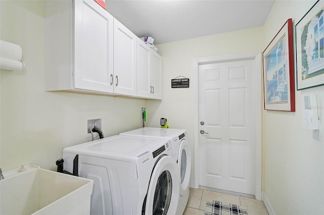 laundry area with cabinets, separate washer and dryer, sink, and light tile patterned floors