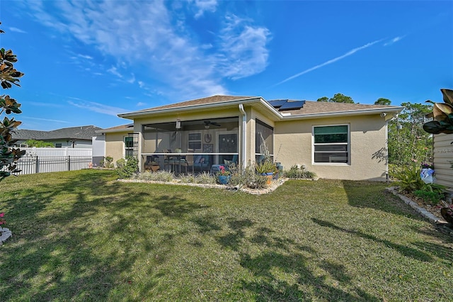 rear view of property featuring a sunroom, solar panels, and a yard