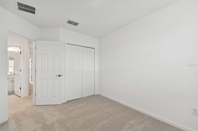 unfurnished bedroom featuring light colored carpet and a closet