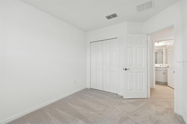 unfurnished bedroom with light carpet and a closet