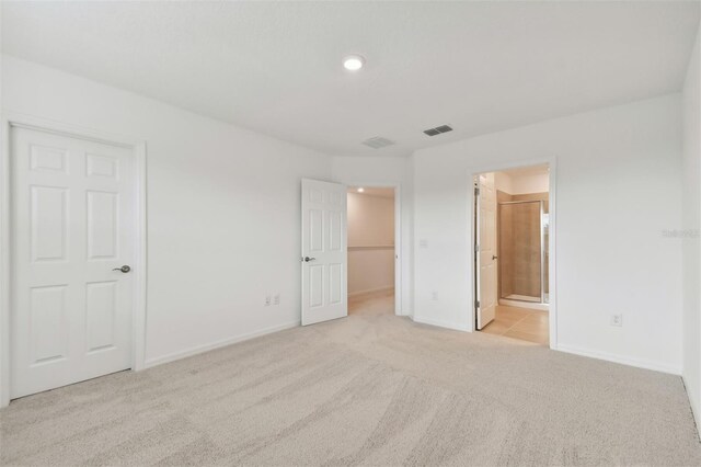 unfurnished bedroom featuring light colored carpet, connected bathroom, and a closet