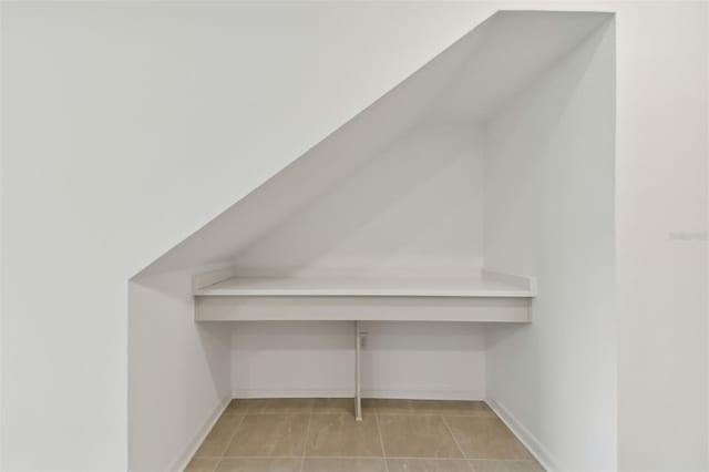 bonus room featuring light tile patterned floors and baseboards