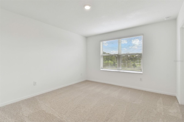 unfurnished room featuring light colored carpet and baseboards