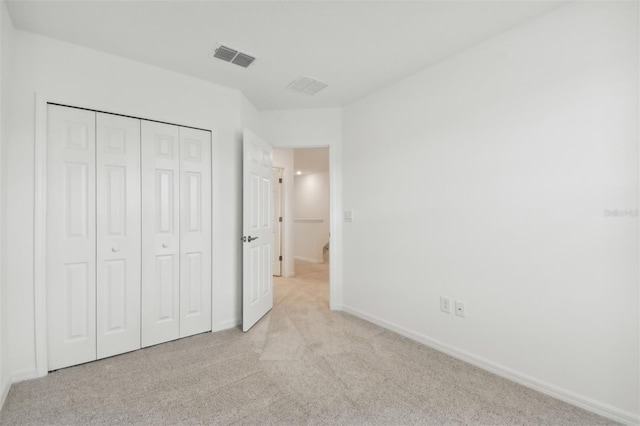 unfurnished bedroom with baseboards, a closet, visible vents, and light colored carpet