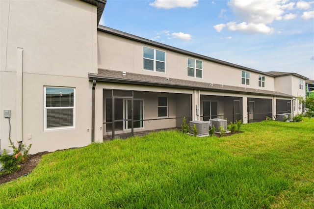 back of property featuring central air condition unit, a yard, a sunroom, and stucco siding