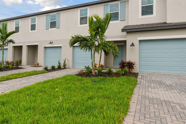 multi unit property with decorative driveway, an attached garage, and stucco siding