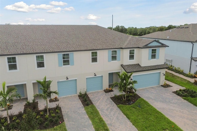 multi unit property with a garage, roof with shingles, and driveway