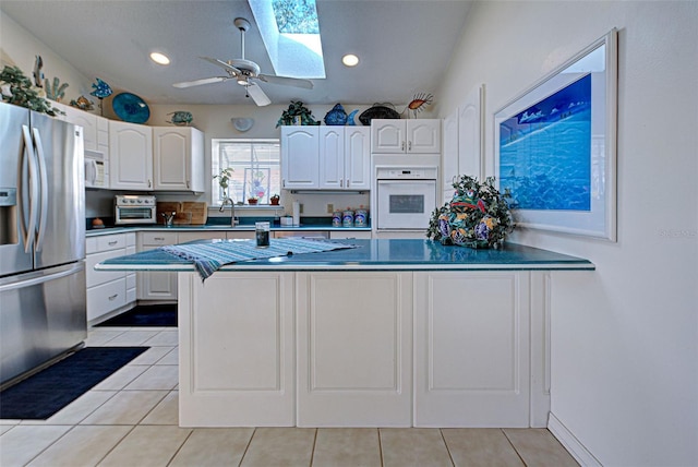 kitchen featuring light tile patterned floors, white appliances, white cabinetry, and sink