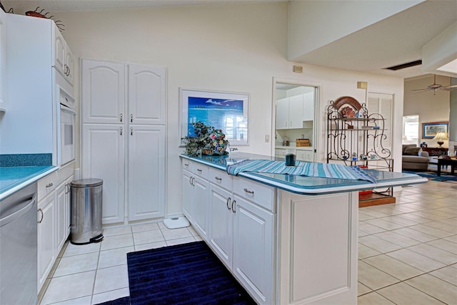 kitchen with kitchen peninsula, white oven, light tile patterned floors, dishwasher, and white cabinets