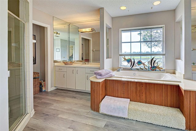 bathroom featuring vanity, wood-type flooring, a textured ceiling, and shower with separate bathtub