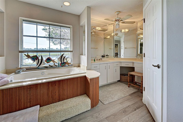 bathroom featuring a bathing tub, ceiling fan, wood-type flooring, a textured ceiling, and vanity