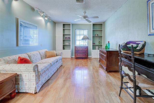 living room with ceiling fan, a textured ceiling, track lighting, and light hardwood / wood-style flooring