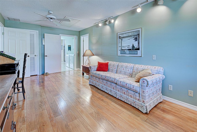 living room with a textured ceiling, ceiling fan, light hardwood / wood-style floors, and track lighting