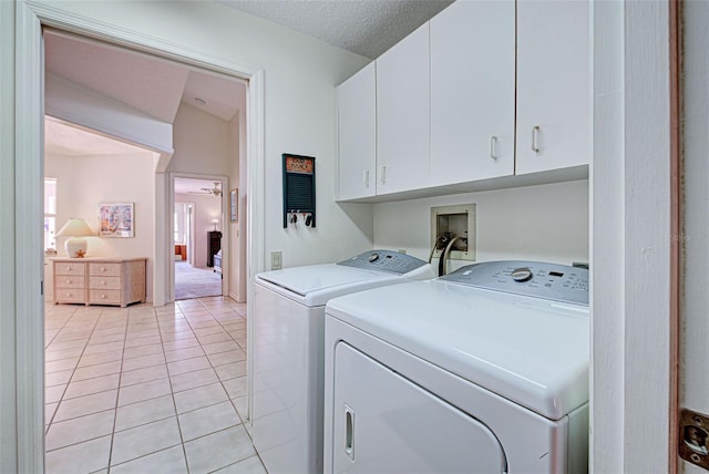 clothes washing area with cabinets, light tile patterned floors, ceiling fan, and washing machine and clothes dryer