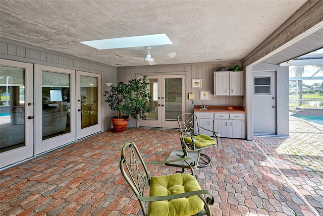 view of patio with a lanai, ceiling fan, and french doors