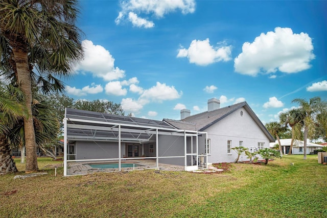 rear view of house featuring a lawn and glass enclosure