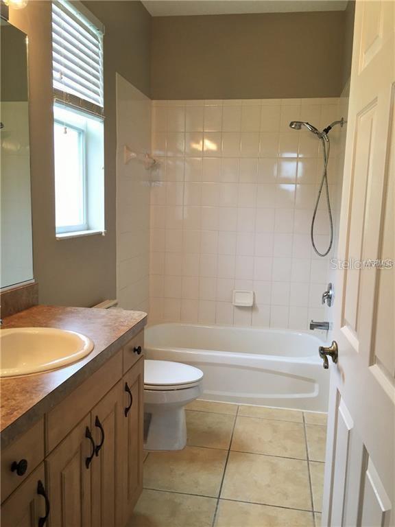 full bathroom with toilet, tile patterned flooring, tiled shower / bath, and vanity