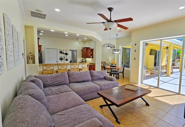 tiled living room with ceiling fan and ornamental molding