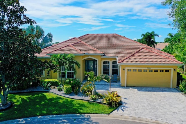 mediterranean / spanish home featuring a garage and a front lawn