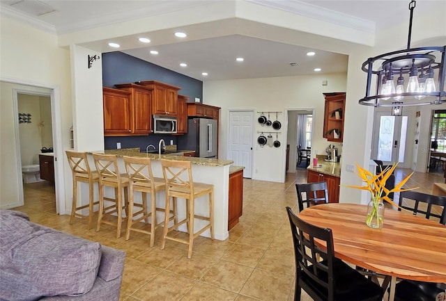 kitchen with stainless steel appliances, crown molding, light tile patterned floors, and kitchen peninsula