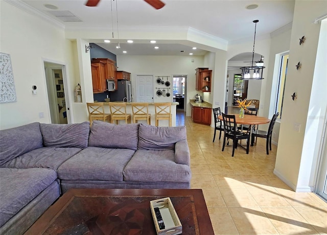 living room featuring crown molding, ceiling fan with notable chandelier, and light tile patterned floors