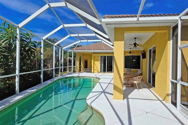 view of swimming pool featuring ceiling fan, glass enclosure, and a patio area