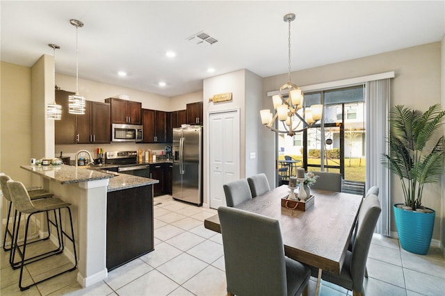 kitchen featuring kitchen peninsula, decorative light fixtures, light tile patterned floors, light stone countertops, and stainless steel appliances